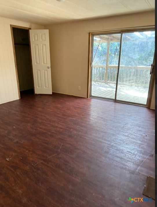 unfurnished bedroom with access to exterior and dark hardwood / wood-style flooring