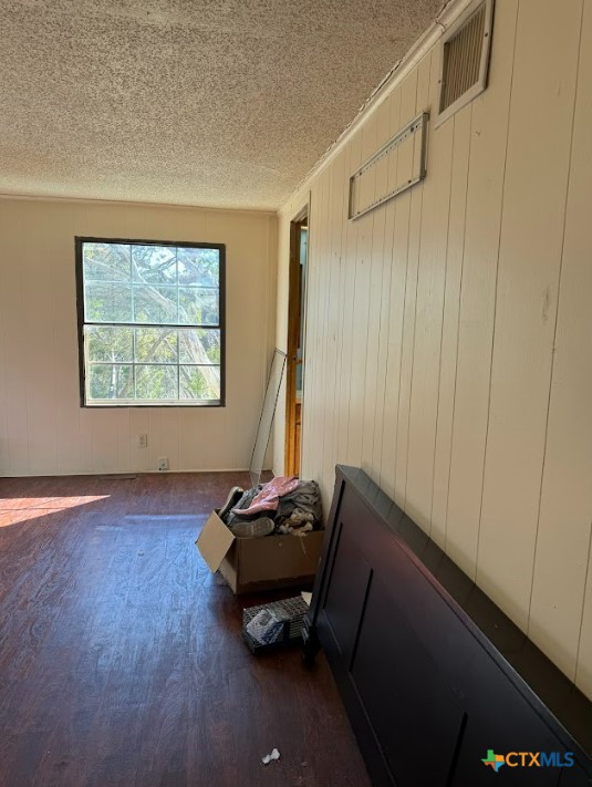 unfurnished room with crown molding, dark hardwood / wood-style floors, and a textured ceiling