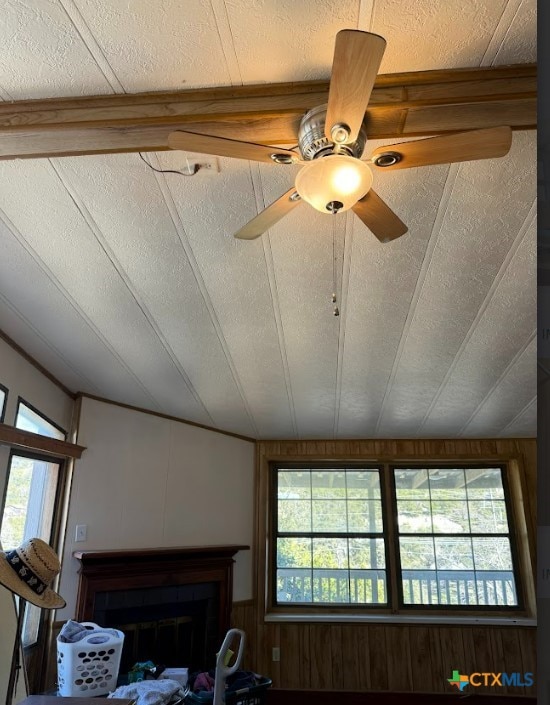 interior details with ceiling fan, a textured ceiling, and wooden walls