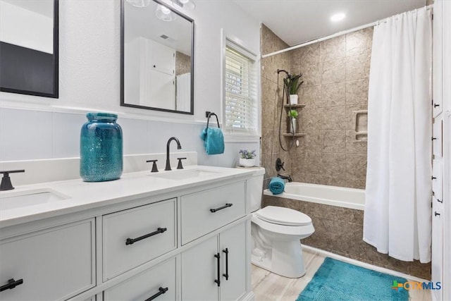 bathroom featuring a sink, tiled shower / bath, toilet, and double vanity