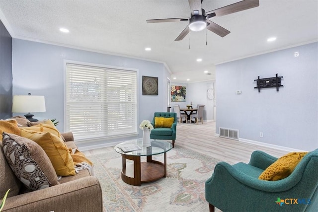 living area featuring baseboards, visible vents, a textured ceiling, crown molding, and recessed lighting