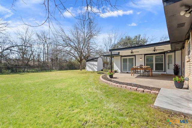 view of yard with an outbuilding, a patio, a ceiling fan, fence, and a shed