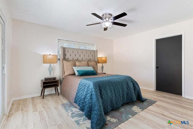 bedroom with light wood-style floors, a textured ceiling, baseboards, and a ceiling fan