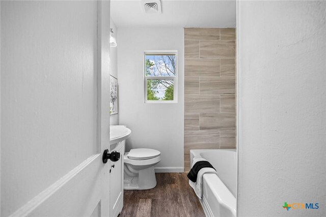 1304 E French Ave, Temple, TX 76501 - bathroom featuring a tub to relax in, wood finished floors, toilet, a shower, and baseboards