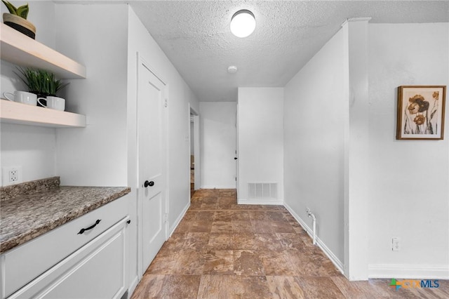 1304 E French Ave, Temple, TX 76501 - hall featuring a textured ceiling, baseboards, and stone finish floors