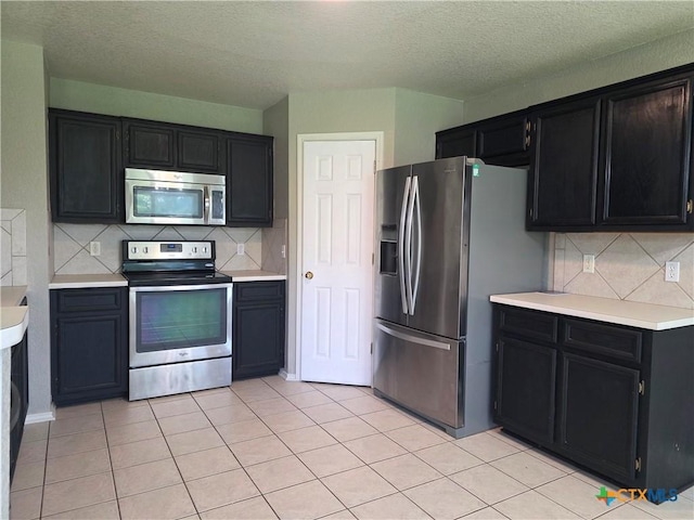 2803 Lindsey Dr, Copperas Cove, TX 76522 - kitchen featuring stainless steel appliances, dark cabinetry, light countertops, a textured ceiling, and backsplash