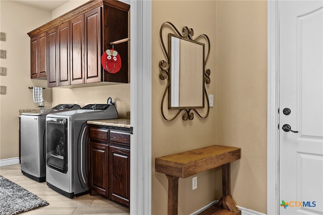 clothes washing area with cabinets and independent washer and dryer