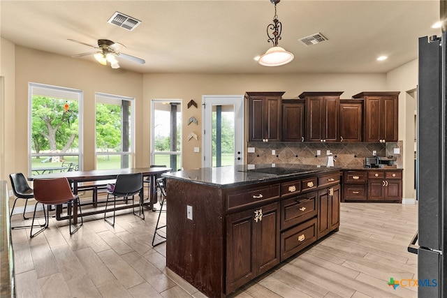 kitchen with black electric stovetop, dark brown cabinetry, pendant lighting, light hardwood / wood-style floors, and a center island