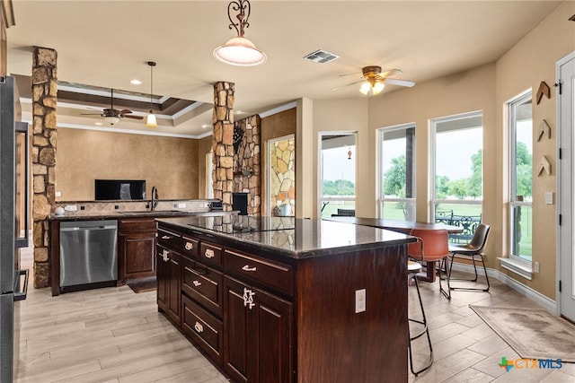 kitchen featuring a breakfast bar, decorative light fixtures, light hardwood / wood-style flooring, a kitchen island, and dishwasher