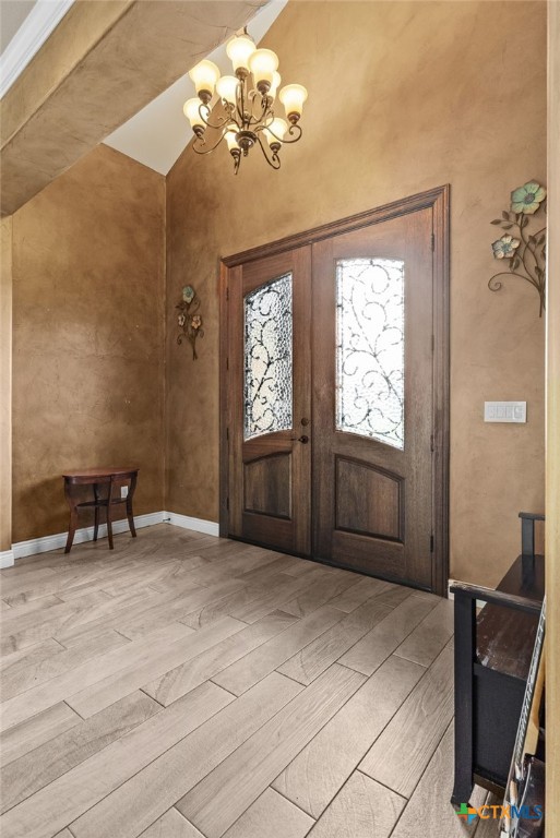 entrance foyer with an inviting chandelier, light hardwood / wood-style flooring, and french doors