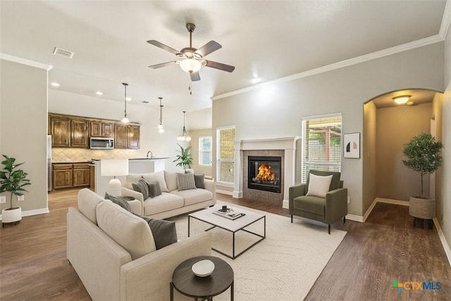 1617 Shadow Canyon Dr, Temple, TX 76502 - living area with arched walkways, ceiling fan, wood finished floors, ornamental molding, and a tile fireplace