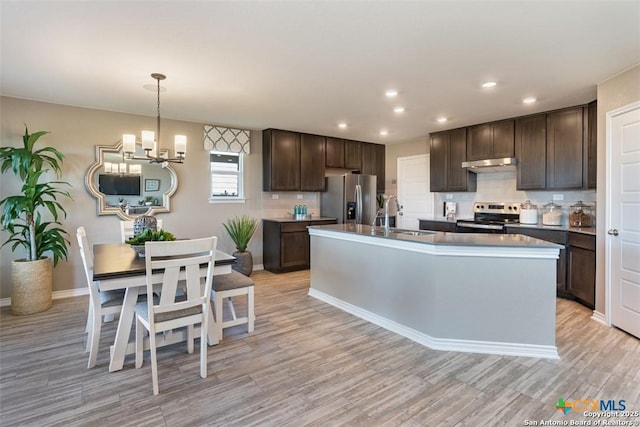 kitchen featuring sink, dark brown cabinets, hanging light fixtures, appliances with stainless steel finishes, and an island with sink