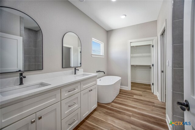 bathroom with vanity, hardwood / wood-style flooring, and a tub to relax in