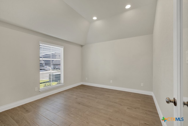 empty room with light wood-type flooring and lofted ceiling