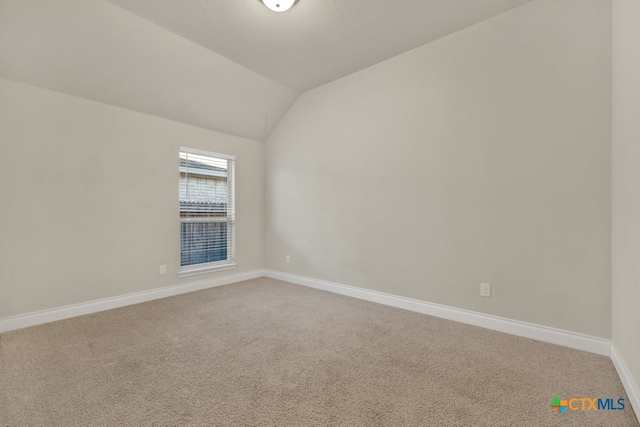 empty room with carpet floors and lofted ceiling