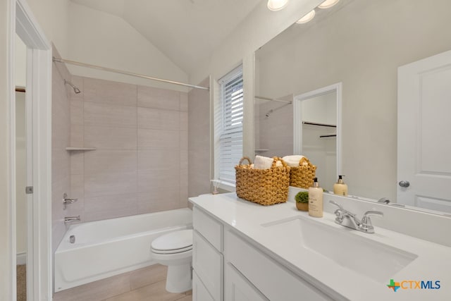 full bathroom featuring lofted ceiling, tile patterned floors, toilet, tiled shower / bath combo, and vanity