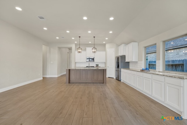 kitchen with white cabinets, appliances with stainless steel finishes, light hardwood / wood-style floors, and decorative light fixtures