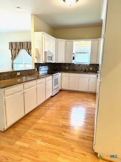 kitchen featuring dark stone counters, white cabinetry, white appliances, and light wood-type flooring