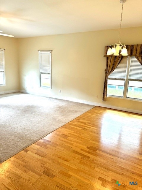 unfurnished room with light wood-type flooring and a notable chandelier