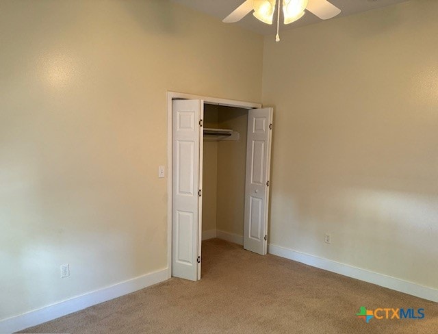 unfurnished bedroom with ceiling fan, light carpet, and a closet