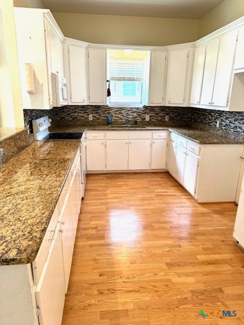 kitchen with light hardwood / wood-style floors, white cabinets, electric range oven, backsplash, and dark stone countertops