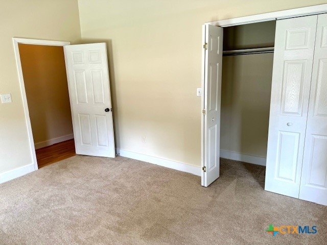 unfurnished bedroom featuring light carpet and a closet