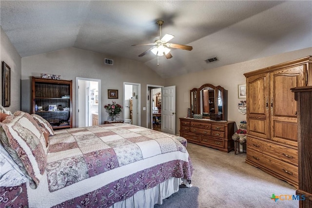 bedroom with lofted ceiling, ensuite bathroom, light colored carpet, a textured ceiling, and ceiling fan