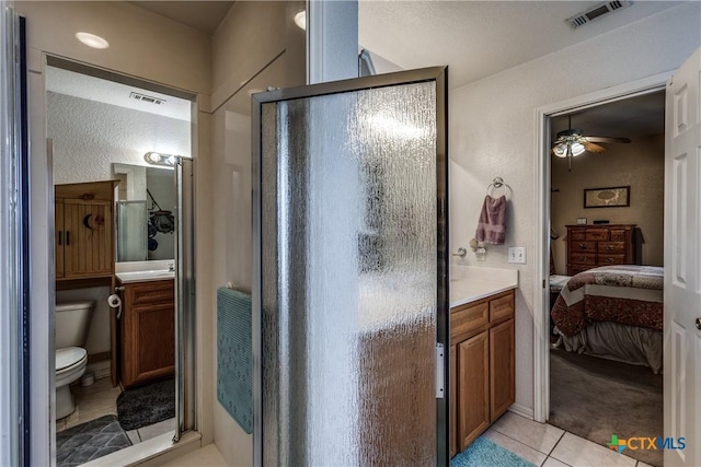 bathroom featuring tile patterned floors, toilet, a shower with shower door, and vanity