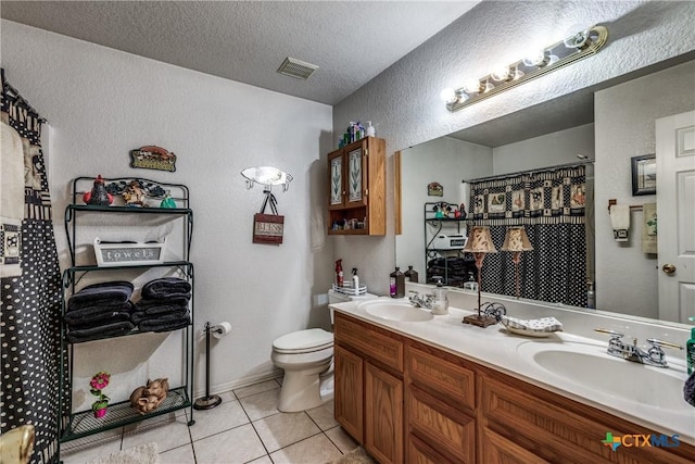 bathroom featuring tile patterned flooring, vanity, toilet, and a textured ceiling