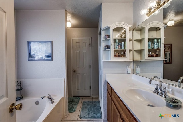 bathroom featuring tile patterned flooring, vanity, a bathtub, and a textured ceiling