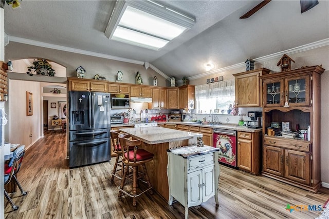 kitchen featuring lofted ceiling, a center island, light wood-type flooring, a kitchen breakfast bar, and stainless steel appliances