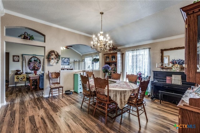 dining room with lofted ceiling, a notable chandelier, wood-type flooring, ornamental molding, and a textured ceiling