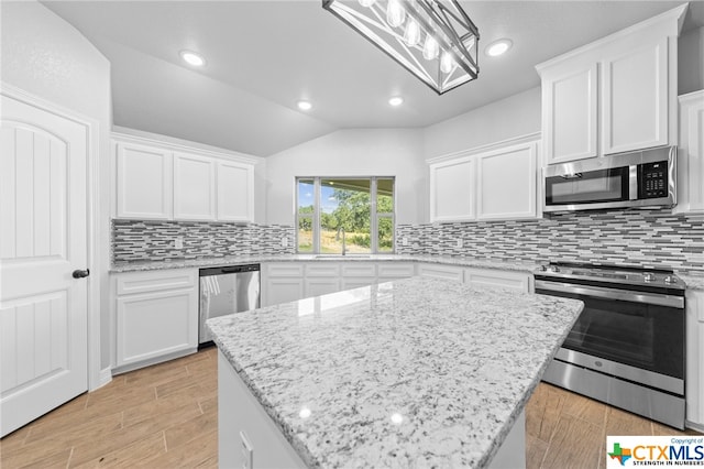 kitchen with white cabinets, appliances with stainless steel finishes, lofted ceiling, and pendant lighting