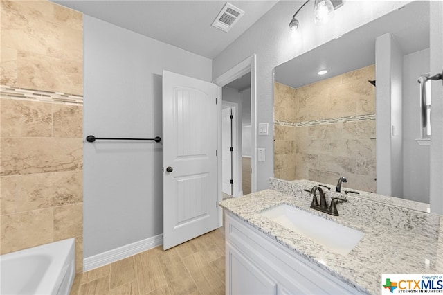 bathroom with wood-type flooring, vanity, and tiled shower / bath