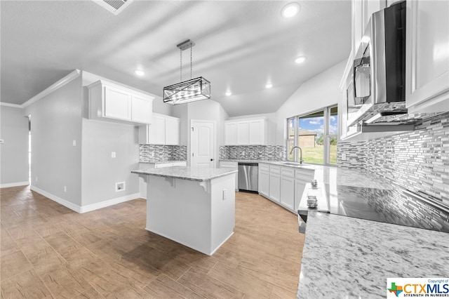 kitchen featuring stainless steel appliances, white cabinetry, decorative light fixtures, a center island, and decorative backsplash