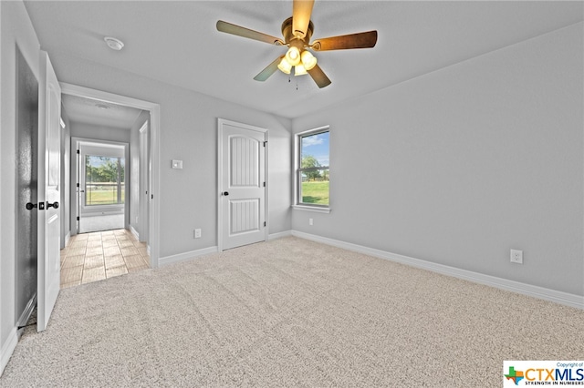 unfurnished bedroom with ceiling fan, multiple windows, and light carpet