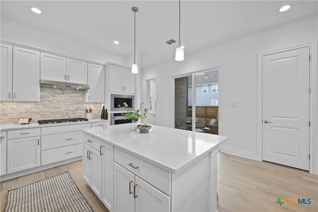 kitchen featuring white cabinetry, stainless steel appliances, a center island, tasteful backsplash, and decorative light fixtures