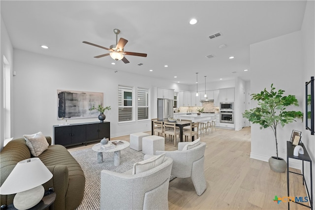 living room featuring ceiling fan and light hardwood / wood-style flooring