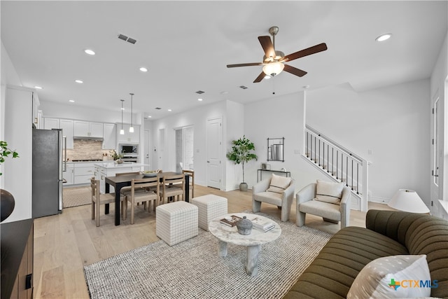 living room featuring light hardwood / wood-style flooring and ceiling fan