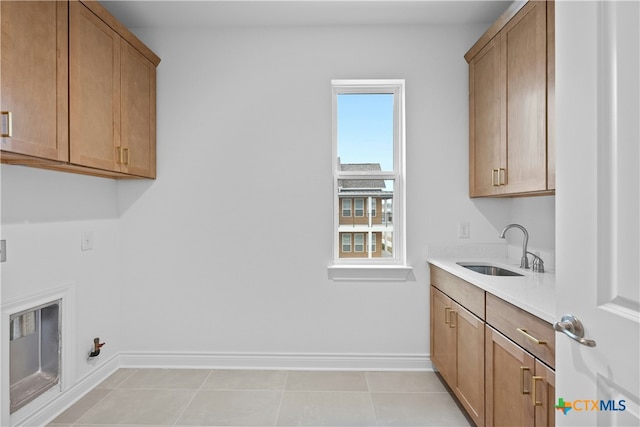 clothes washing area with cabinets, sink, light tile patterned floors, and hookup for a gas dryer