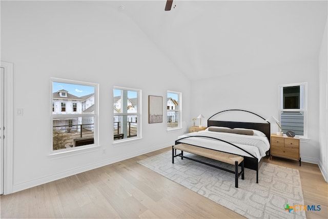 bedroom with ceiling fan, high vaulted ceiling, and light wood-type flooring