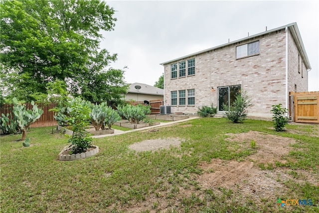 rear view of property with central AC unit and a lawn