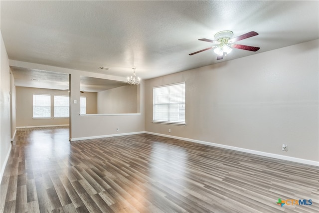 empty room with a textured ceiling, wood-type flooring, and ceiling fan with notable chandelier