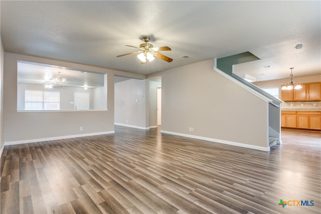 unfurnished living room featuring dark hardwood / wood-style flooring, a textured ceiling, and ceiling fan with notable chandelier