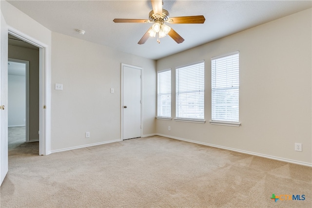 spare room with light colored carpet and ceiling fan