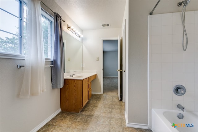 bathroom with vanity, tile patterned floors, a textured ceiling, and tiled shower / bath combo