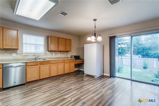 kitchen featuring stainless steel appliances, light hardwood / wood-style floors, sink, an inviting chandelier, and decorative backsplash