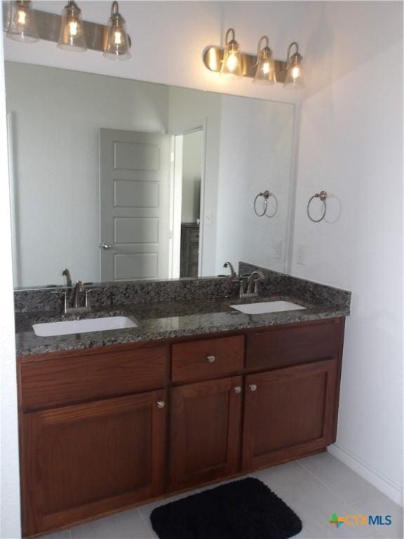 bathroom with baseboards, tile patterned flooring, a sink, and double vanity