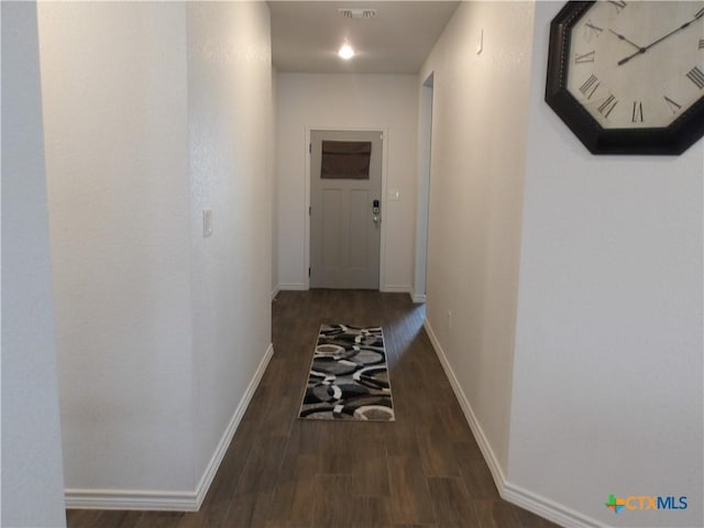 hall featuring visible vents, baseboards, and wood finished floors