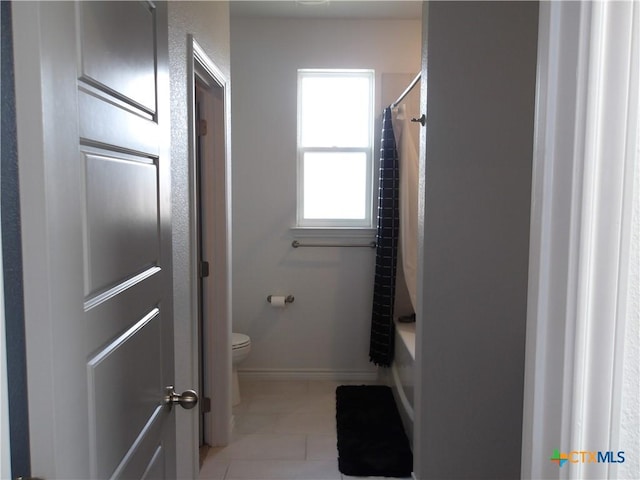 bathroom with tile patterned flooring, shower / tub combo with curtain, toilet, and baseboards